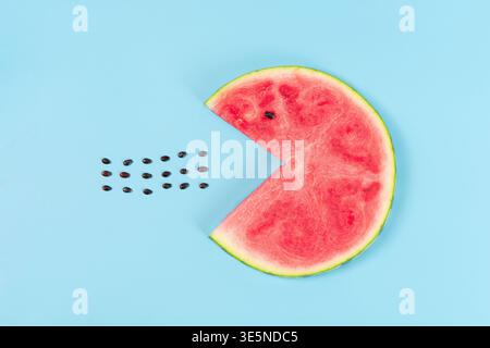 Wassermelonenscheibe, die pac-man-Samen auf blauem Hintergrund imitiert Stockfoto