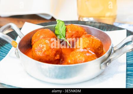 Traditionelle Fleischbällchen serviert mit Basilikumblatt und Tomatensauce. Italienisches Restaurant Osteria in Turin, Norditalien. Stockfoto