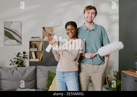 Porträt eines vielfältigen Paares, das Haus für Haushaltsarbeit reinigt Stockfoto