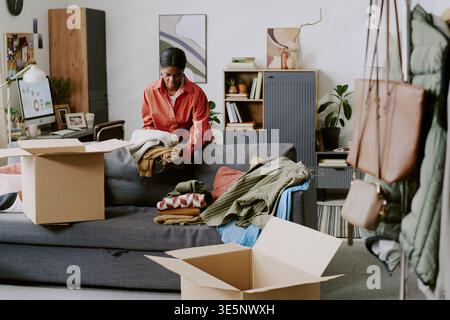 Schwarze Frau, die Kleidungsbestellungen für den Online-Wiederverkauf aufnimmt Stockfoto