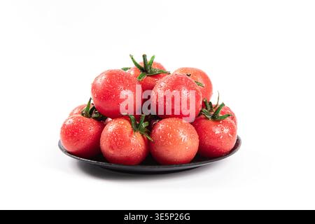 Frische Kirschtomaten, bedeckt mit Wassertropfen auf einer schwarzen Platte Stockfoto