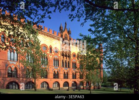 Geschmückte viktorianische Fassade aus rotem Backstein der Templeton's Carpet Factory auf Glasgow Green, eingerahmt von Bäumen und Sonnenlicht. Ein eindrucksvolles Beispiel der historischen Gotik Stockfoto