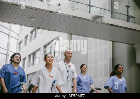 Selbstbewusste männliche und weibliche Mediziner gehen in der Lobby des Krankenhauses Stockfoto