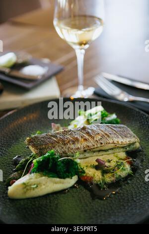 Ein kunstvoll überzogenes Fischgericht, garniert mit frischem Gemüse und Sauce, bietet ein köstliches Erlebnis Stockfoto