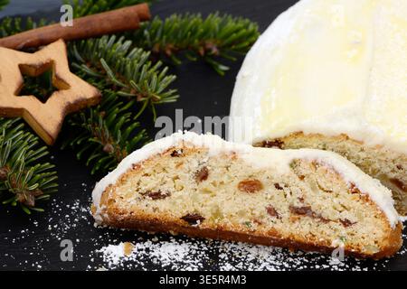 weihnachtsstollen mit Tannenzweig, Sternen und Zimtstäbchen liegen zur weihnachtszeit auf schwarzem Schiefer Stockfoto