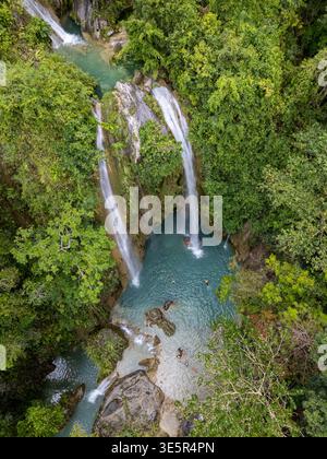 Cebu, Philippinen – 9. April 2025: Die Menschen schwimmen im türkisfarbenen Pool unterhalb der Inambakan Falls, umgeben von dichten tropischen Wäldern, aus der Vogelperspektive. Stockfoto