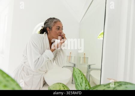 Kosmetikbereich im Spa-Stil mit rundem Waschbecken und Chrom-Wasserhahn und Topftisch für Pflanzen Stockfoto