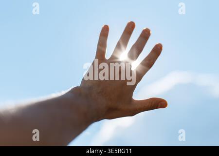 Der Mann hob seine Hand zur Sonne und die Sonnenstrahlen scheinen durch seine Finger. Freiheit, Konzept Stockfoto