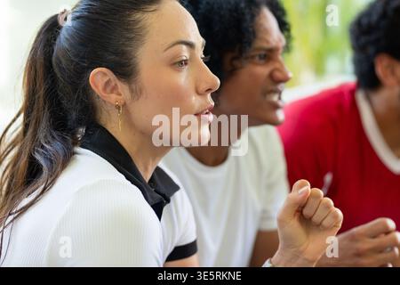 Verschiedene Freunde, die in der Lounge spielen, Frau mit Pferdeschwanz, goldenen Ohrring, Mann mit Faust Stockfoto