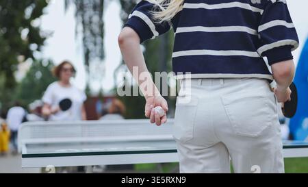 Junge Frau, die während eines Tischtennisspiels im Freien dient und einen aktiven Lebensstil genießt Stockfoto