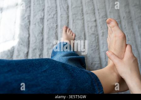 Eine Nahaufnahme zeigt eine Hand, die sanft einen Fuß massiert, wodurch Selbstpflege und Entspannung hervorgehoben werden. Dieses Bild eignet sich für Wellness-, Gesundheits- und Lifestyle-Inhalte. Stockfoto