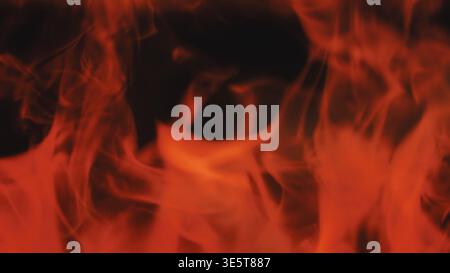 Rote und orangene Flammen, die hell auf dunklem Hintergrund brennen und Wärme und Energie veranschaulichen Stockfoto