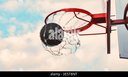 Ein flacher Actionschuss eines schwarzen Basketballs, der mit einem Kettennetz durch einen roten Metallkorb schwebt. Die Bewegungsunschärfe fängt den dynamischen Moment des Scori ein Stockfoto
