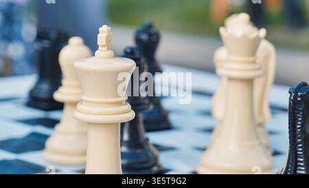 Weißes Königsschach im Fokus auf einem blau-weißen Schachbrett. Strategisches Spielkonzept mit verschwommenem Hintergrund. Stockfoto