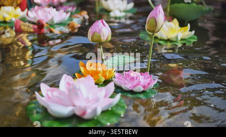 Bunte Plastik-Lotusblumen, die auf einem Teich in Vietnam schwimmen Stockfoto