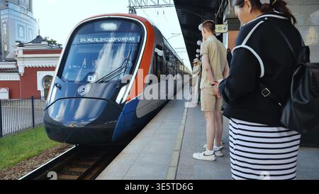 Moskau, Russland - 17. August 2025: Pendler warten auf moderne S-Bahn, die an einem Bahnsteig in Moskau ankommen Stockfoto