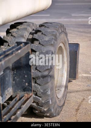 Nahaufnahme von Details zu schweren Maschinen mit Schwerpunkt auf der robusten Textur von Industriereifen und Metallarbeiten. Auf dem Foto sollte ein angezeigt werden Stockfoto