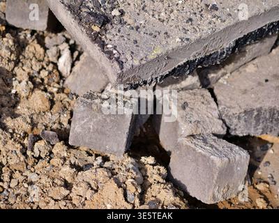 Gebrochene Betonplatten und Kopfsteinpflaster auf einer Baustelle, Haufen abgerissener Pflaster, Industriestruß aus der Nähe, robuste graue Steinstrukturen, e Stockfoto