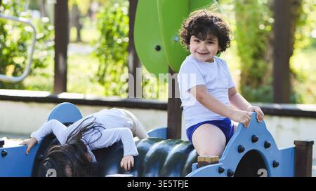 Glückliches Kind lächelt beim Spielen auf einem Spielplatz im Park Stockfoto