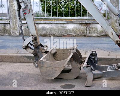 Oberfläche. Der Schuss verfügt über eine verwitterte Grabschaufel und ein schwarzes Planierschild aus Stahl im Vordergrund mit einem Teil des Gummilaufwerks Stockfoto