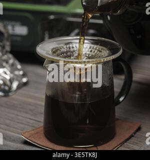 Eine Nahaufnahme des Kaffees, der in eine Glaskaraffe gegossen wird, zeigt die satte Farbe und den Brühprozess Stockfoto