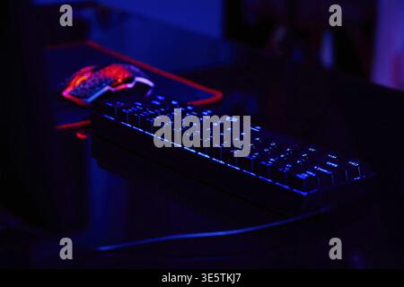 PC mit rgb-Tastatur für Gaming-Computer-Videospiele mit neonfarbenem Hintergrund, dunkler Raum mit Spielearbeitsplatz ohne Menschen Stockfoto