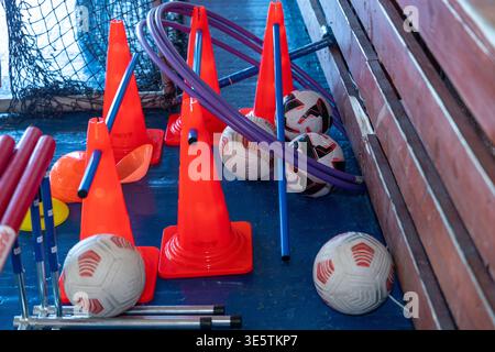 In hellen Farben gehaltener Fitnessraum mit verschiedenen Soft-Play-Geräten, einschließlich Schaumstoffblöcken, großen Ringen und Bälle, die über den Boden verteilt sind. Orangefarbene Verkehrskegel Stockfoto