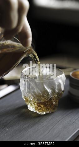Ein atemberaubender Blick aus der Nähe des reichhaltigen Whiskeys, der anmutig in ein wunderschönes Kristallglas gefüllt mit Eis gegossen wird Stockfoto