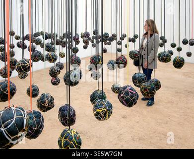 Eine Frau läuft in der hängenden Playtime-Kunstinstallation des kenianischen Künstlers Wangechi Mutu mit Fußbälle aus Plastiktüten, Decken und Seilen Stockfoto