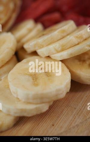 In Scheiben geschnittene Bananen, zubereitet auf einem Holzbrett in der Küche Stockfoto