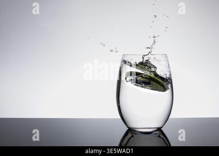 Kalkscheibe spritzt in Glas Wasser mit dynamischem Spritzen auf weißem Hintergrund und Kopierraum Stockfoto