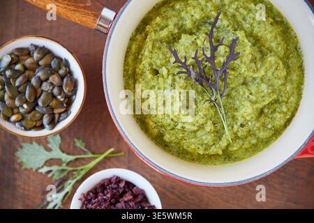 Oben, Guacamole und Kürbiskerne auf dem Tisch mit gesunder Nahrung, Mahlzeitzubereitung und veganer Ernährung. Pflanzliche Küche und Avocado-Dip in der Pfanne mit Stockfoto
