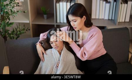 Mutter tröstet ihr krankes Kind zu Hause Stockfoto