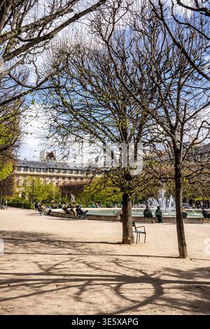 Einheimische und Besucher entspannen sich am runden Brunnen in den eleganten Gärten des Palais Royal, einer beliebten grünen Oase in Paris, Frankreich Stockfoto