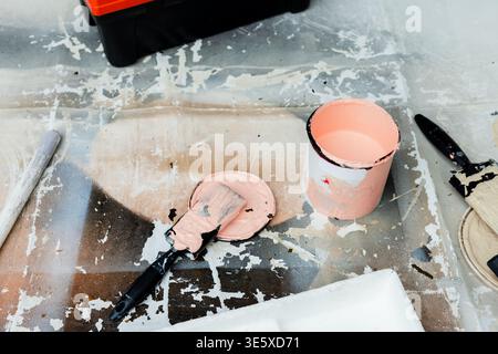 Offene Lackdose auf Tuch im Renovierungsarbeitsplatz, Spachtelmesser auf Deckel aufliegend, Bürstentrocknung Stockfoto
