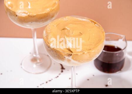 Dalgona Espresso-Martini-Cocktail mit Schlagsahne und cremigem Likör, viraler Sommercocktail in zwei Martini-Gläsern, mit Shaker und Bar-ut Stockfoto