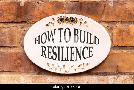 So erstellen Sie ein Resilienzsymbol. Konzeptworte wie man Widerstandsfähigkeit auf einem schönen weißen Schild schafft. Wunderschöner Backsteinmauerhintergrund. Geschäftsanweisungen Stockfoto