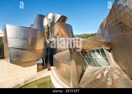 Besucher erkunden das Guggenheim Museum in Bilbao. Die Struktur zeigt modernes Design mit reflektierenden Oberflächen. Klares Wetter verbessert die Sicht. Stockfoto
