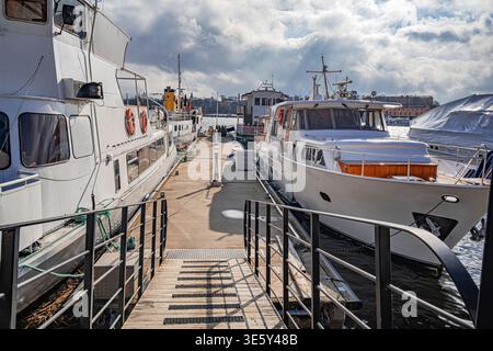 Weiße Vintage-Passagierschiffe und moderne Yachten liegen an einem Betonpier im Stockholmer Hafen an. Stockfoto