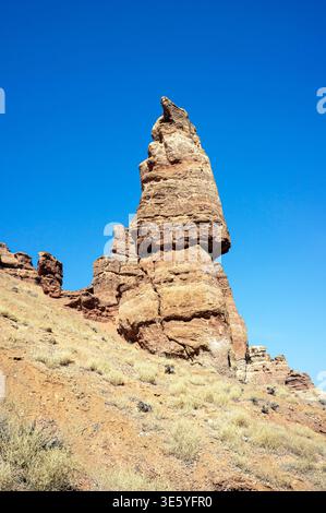 Niedriger Blickwinkel auf eine hoch aufragende vertikale Sandsteinformation, die einem Burgturm vor einem klaren blauen Himmel im Charyn Canyon in Kasachstan ähnelt Stockfoto