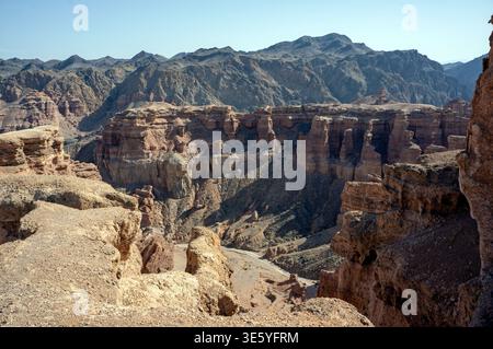 Malerischer Blick auf die mehrschichtige Sandsteinarchitektur und die Wüstengebirge rund um das tiefe Tal der Schlösser in Charyn National Par Stockfoto