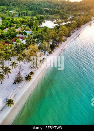 Aus der Vogelperspektive auf das türkisfarbene Meer, das sanft den unberührten weißen Sand küsst, gesäumt von grünen Bäumen, Preah Sihanouk, Sihanoukville, Kambodscha. Stockfoto