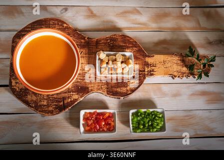 Eine Schüssel Gazpacho, das begleitende Gemüse und geröstetes Brot. Stockfoto