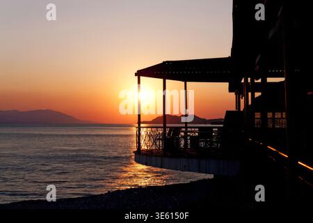 Sonnenuntergang über dem Meer von der Terrasse am Meer aus, Griechenland Stockfoto