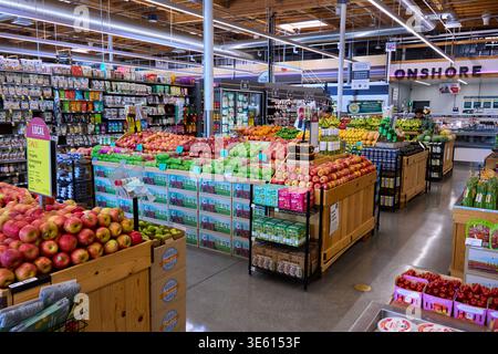 Das Innere eines modernen Bio-Lebensmittelgeschäfts mit frischem Obst und Gemüse. Große Auswahl an Äpfeln, Zitrusfrüchten und lokalen Produkten in Regalen. Stockfoto