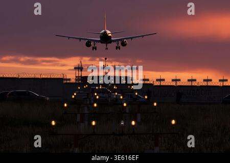Airbus A320 landet bei Sonnenuntergang auf beleuchteten Anfluglichtern am Flughafen Sheremetjewo Stockfoto