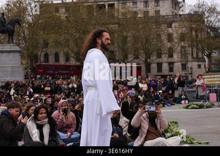 London, UK . April 2026. Jesus steigt aus den Menschenmassen vor der National Gallery für die jährliche Nachstellung des biblischen Stücks von Wintershall auf. Die Menschenmassen sitzen eng zusammen, während ein Darsteller Jesus während einer immersiven Passion of Christ-Performance am Trafalgar Square darstellt. Eine moderne Nacherzählung der Passion Christi entfaltet sich unter den Zuschauern auf dem Trafalgar Square, die Theater und öffentlichen Raum bei Osterveranstaltungen miteinander verbindet. Quelle: Desislava Lizova/Alamy Live News Stockfoto