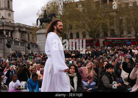 London, UK . April 2026. Jesus steigt aus den Menschenmassen vor der National Gallery für die jährliche Nachstellung des biblischen Stücks von Wintershall auf. Die Menschenmassen sitzen eng zusammen, während ein Darsteller Jesus während einer immersiven Passion of Christ-Performance am Trafalgar Square darstellt. Eine moderne Nacherzählung der Passion Christi entfaltet sich unter den Zuschauern auf dem Trafalgar Square, die Theater und öffentlichen Raum bei Osterveranstaltungen miteinander verbindet. Quelle: Desislava Lizova/Alamy Live News Stockfoto