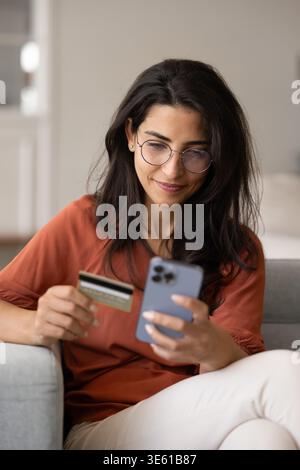 Junge lächelnde Frau der 30er Jahre, die online bezahlt Stockfoto