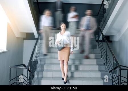 Geschäftiges Büroleben. Mitarbeiter, die Treppen im Gebäude hinuntergehen, Bewegungsunschärfe-Effekt Stockfoto